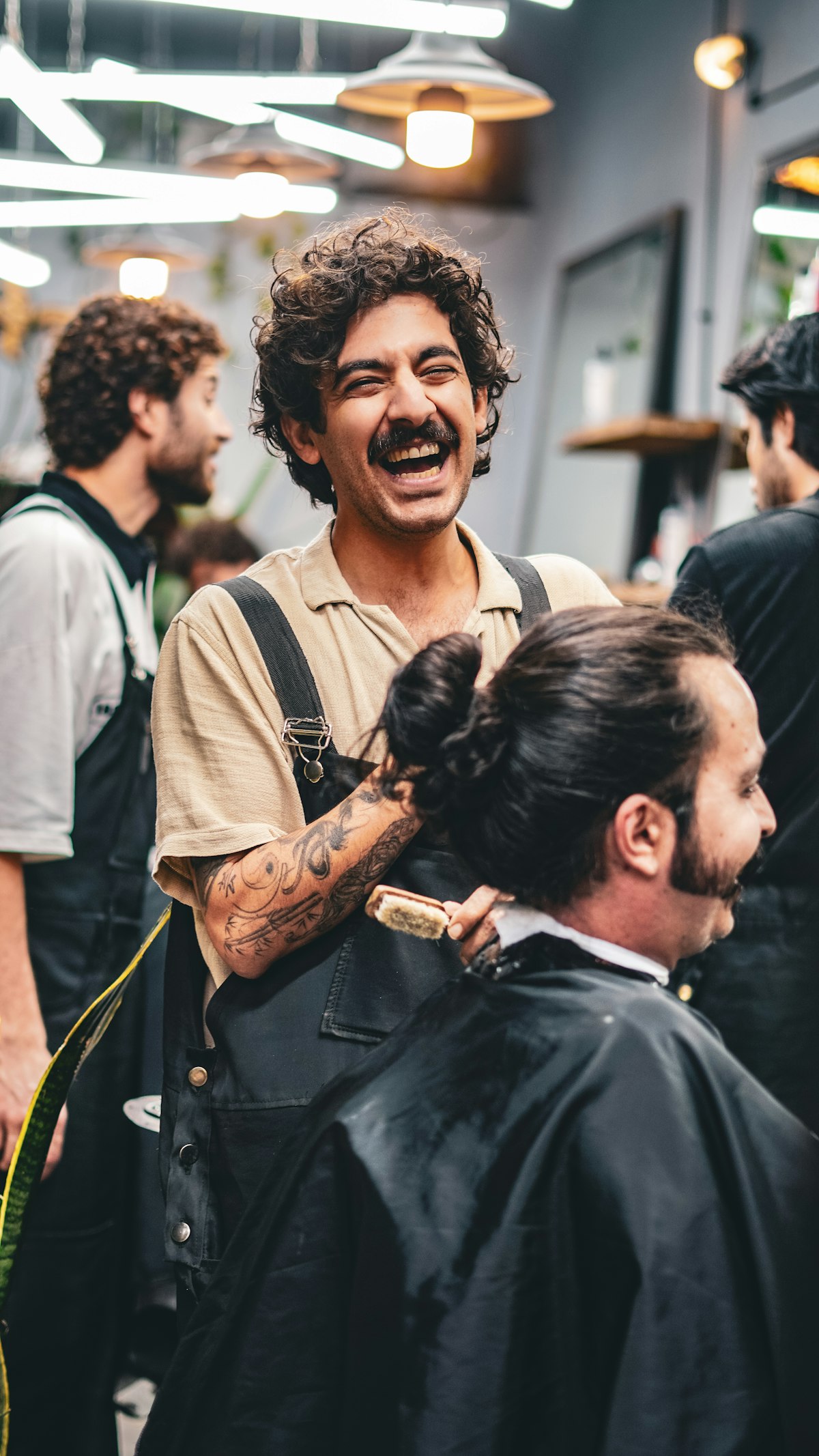 Barbeiro sorrindo enquanto corta o cabelo de um cliente